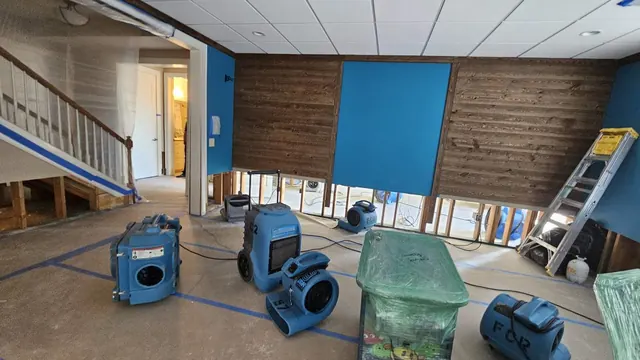 Air movers and dehumidifiers drying a flood-cut room