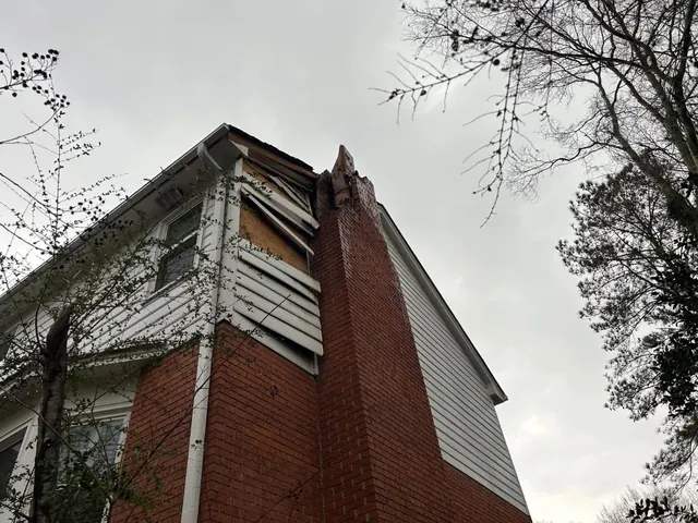 Exterior structural damage near chimney and roofline following impact
