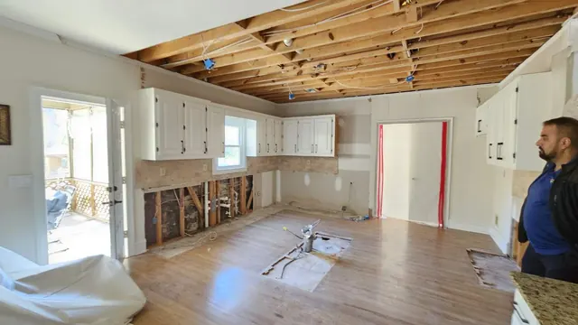 Kitchen with ceiling drywall removed and plumbing wall exposed for inspection