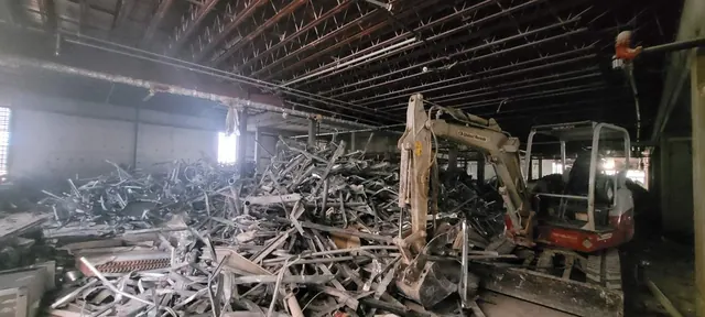 Mini excavator processing metal framing during commercial interior demolition